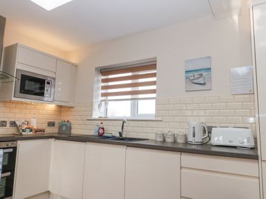 A kitchen with white cabinets a microwave kettle toaster and containers on the counter at Weydale Avenue Scarborough