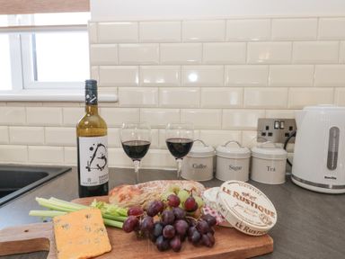 A kitchen countertop with wine bottle glasses bread cheese celery grapes and canisters at Weydale Avenue in Scarborough