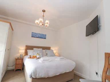 A bedroom with a double bed bedside tables lamps a wall-mounted TV and a wardrobe at Weydale Avenue in Scarborough