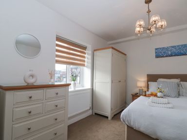 A bedroom with a bed a wardrobe a chest of drawers a window and a bedside table at Weydale Avenue in Scarborough