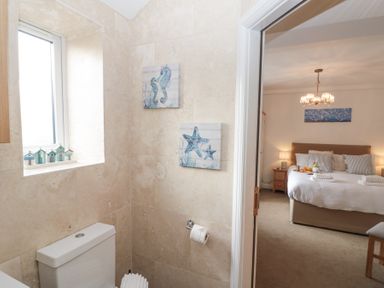 A bathroom with a toilet and nautical wall art next to a bedroom with a bed and bedside tables at Weydale Avenue in Scarborough