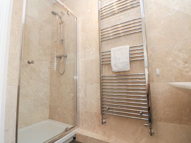 A shower with glass door and a wall-mounted towel radiator with a white towel at Weydale Avenue in Scarborough