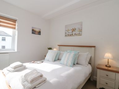 A bedroom with a double bed with striped pillows bedside tables with lamps and folded towels on the bed at Weydale Avenue in Scarborough