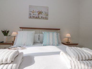 A bedroom with a bed striped pillows towels on the bed lamps and a painting on wall at Weydale Avenue in Scarborough