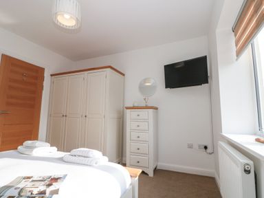 A bedroom with a bed with folded towels dresser wardrobe wall mounted television and window at Weydale Avenue in Scarborough