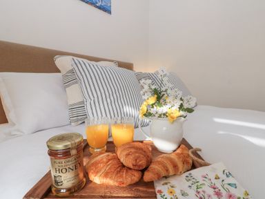 A bed with striped pillows and a breakfast tray with croissants honey glasses of juice and a flower jug at Weydale Avenue Scarborough