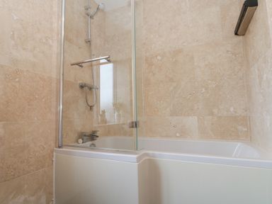 A bathroom with a bathtub shower combination and beige tiled walls at Weydale Avenue in Scarborough