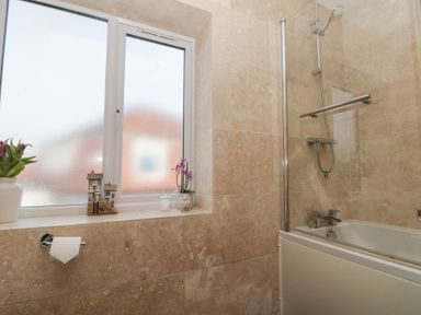 A bathroom with a frosted window a bathtub with shower fixtures and decorations on the windowsill at Weydale Avenue in Scarborough