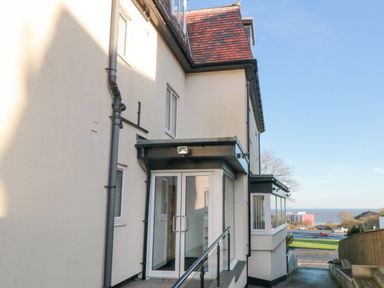 Entrance door with glass panels to a building and a view of a road and sea beyond at Weydale Avenue in Scarborough