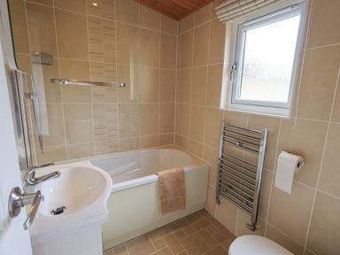 A bathroom with a bathtub shower sink towel rail and toilet paper holder at Esthwaite Lodge Beckside 43 Limefitt Park near Windermere