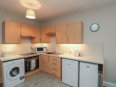 A kitchen with appliances including a washing machine, oven, and microwave at Beck View