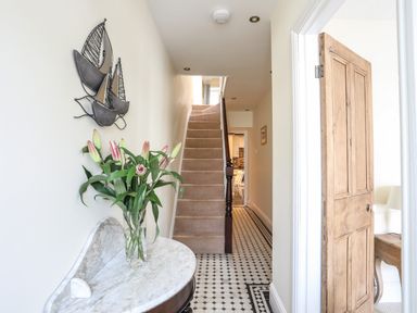 A hallway with a staircase a wooden door and a marble table with flowers at Hyfrydle in Borth-Y-Gest