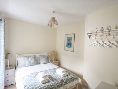 A bedroom with a double bed lamps on bedside tables and hangers on the wall at Hyfrydle in Borth-Y-Gest