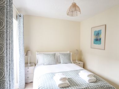 A bedroom with a bed two bedside tables lamps and a framed picture at Hyfrydle in Borth-Y-Gest