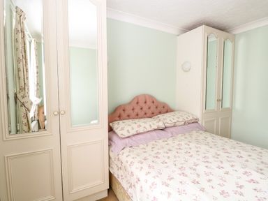 A bedroom with a bed with floral bedding and two mirrored wardrobes at Ellan Vannin in Sheringham