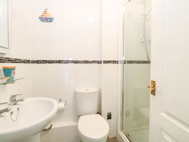 A small bathroom with a sink toilet and shower at Ellan Vannin in Sheringham