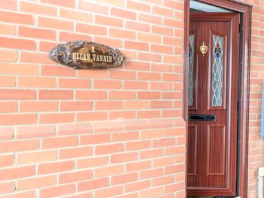 A brown brick wall with a wooden door and a decorative sign reading 1 Ellan Vannin at Ellan Vannin Sheringham