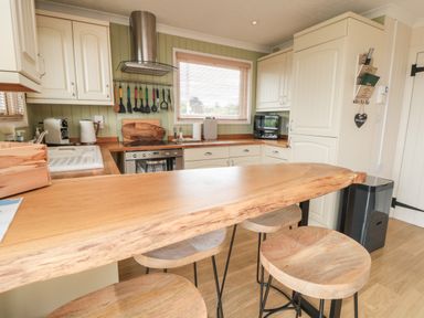 A kitchen with wooden countertops stools cooking utensils and appliances at 3 Valley View Lodges Nawton near Helmsley