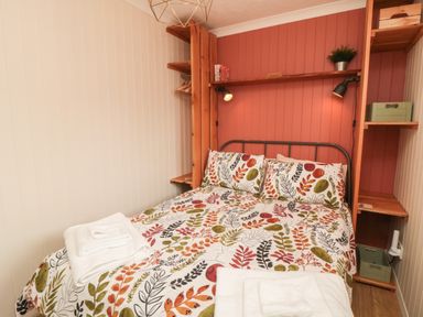 A bedroom with a double bed with floral bedding and towels on the bed at 3 Valley View Lodges Nawton near Helmsley
