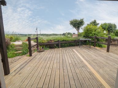 A wooden decked patio area with a small table and railing overlooking a garden and countryside at 3 Valley View Lodges Nawton near Helmsley