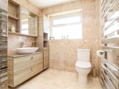 A bathroom with a wooden vanity unit and sink a toilet and a towel warmer at Summerhayes in Park Bottom