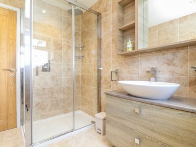 A bathroom with a glass shower enclosure a white basin on wooden vanity and a wooden door at Summerhayes in Park Bottom