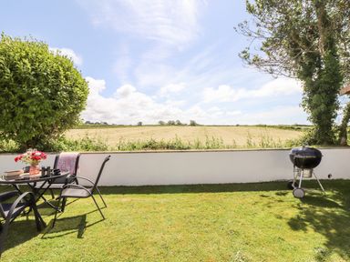 Outdoor garden area with a table and chairs and a barbecue grill overlooking a field at Summerhayes in Park Bottom