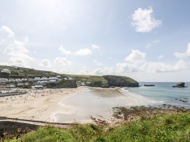 A beach with people on the sand and houses on the hillside at Summerhayes Park Bottom