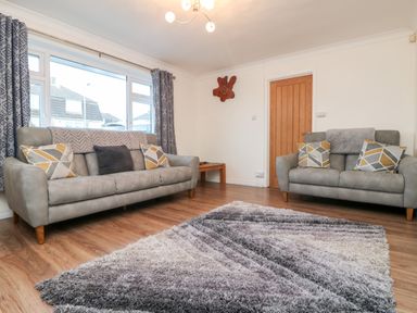 A living room with two gray sofas a wooden door and a patterned rug on a wooden floor at Summerhayes Park Bottom
