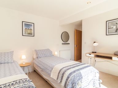 A bedroom with two single beds a small round table with lamp a desk with lamp and a round mirror on the wall at The Croft Thompson near Watton