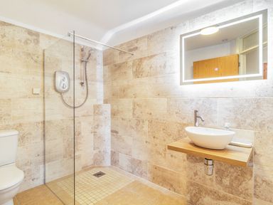 A bathroom with a walk-in shower toilet and a sink with a wooden countertop at The Croft Thompson near Watton