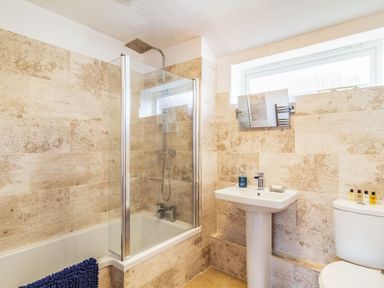 A bathroom with a bathtub and shower enclosure a pedestal sink and a toilet at The Croft in Thompson near Watton