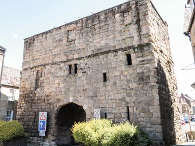 A stone gatehouse with an archway entrance and small windows at Beals Yard in Alnwick