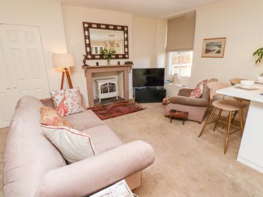 A living room with a sofa and armchair near a fireplace and television at Beals Yard in Alnwick