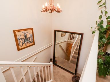 A stairway with a large mirror and a framed painting on the wall with a plant on the right at Beals Yard in Alnwick