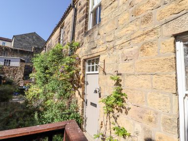 A stone house exterior with a wooden door and climbing plants at Beals Yard in Alnwick