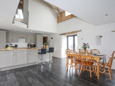 An open kitchen and dining area with wooden dining table and chairs bar stools and kitchen cabinets at Gwel Y Fenai in Y Felinheli