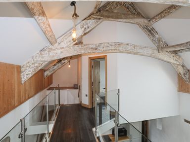 A hallway with exposed wooden beams glass railings and a wooden floor at Gwel Y Fenai in Y Felinheli