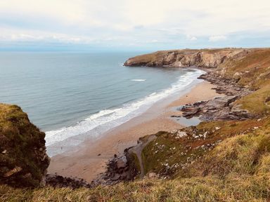 A sandy beach with waves and rocky cliffs surrounding it at Badgers Rest in Tintagel