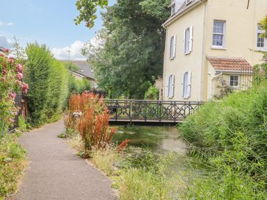A pathway beside a canal with a metal bridge and a yellow house at The Town House in Dorchester