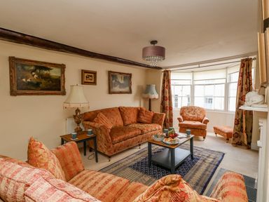 A living room with patterned sofas armchairs coffee table and paintings on the wall at The Town House in Dorchester