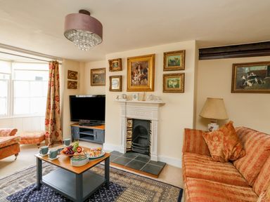 A living room with sofas a coffee table fruit snacks and a television at The Town House in Dorchester