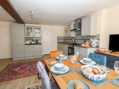A kitchen and dining area with a wooden table set with bowls plates glasses and bread at The Town House in Dorchester
