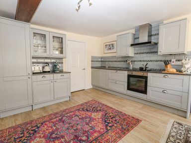 A kitchen with grey cabinets appliances and a colorful rug on the floor at The Town House in Dorchester