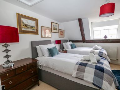 A bedroom with two single beds bedside tables and framed pictures on the wall at The Town House in Dorchester