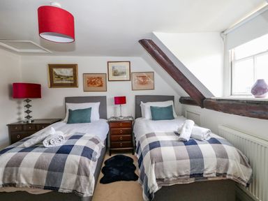 A bedroom with two single beds with checkered blankets and red lamps at The Town House in Dorchester