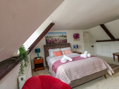 A bedroom with a bed, bedside tables, lamps, and wall art at The Town House in Dorchester