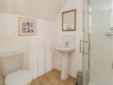 A bathroom with a toilet sink mirror framed floral picture and shower at The Town House in Dorchester