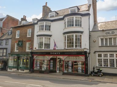 A street view of three buildings with shops on the ground floor including Domvs and St Judes Care at The Town House in Dorchester