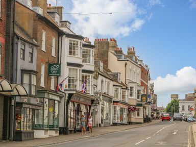 A street with shops buildings cars and people walking at The Town House in Dorchester